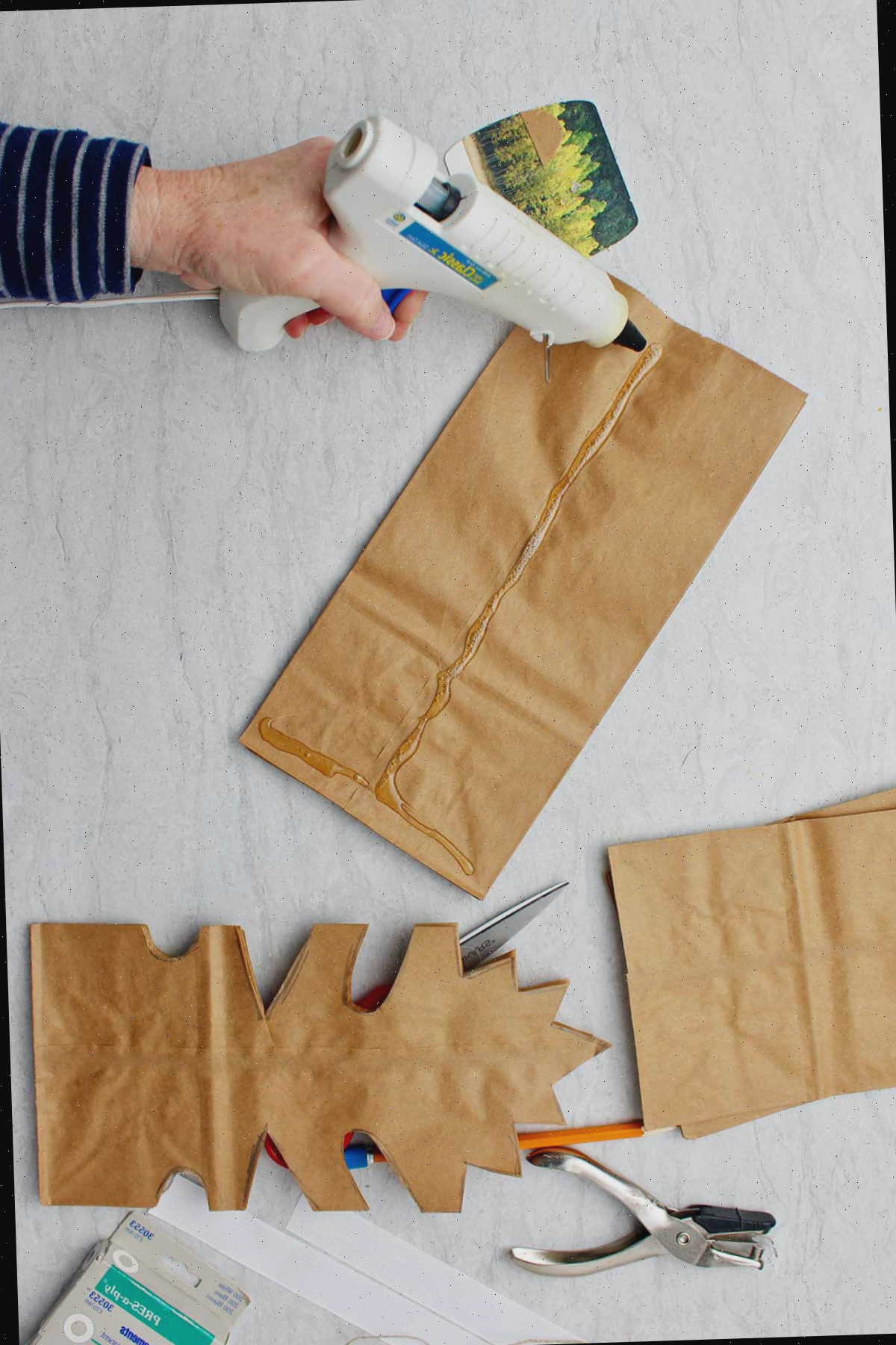 Mão colando sacos de papel marrons juntos antes de cortar.