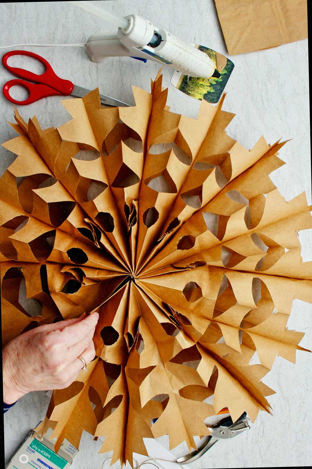 Mão segurando o floco de neve de saco de papel marrom desdobrado.