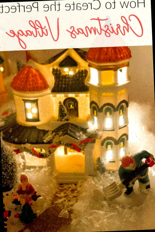 Casinha de vila de Natal em miniatura com pessoas à frente, iluminada à noite