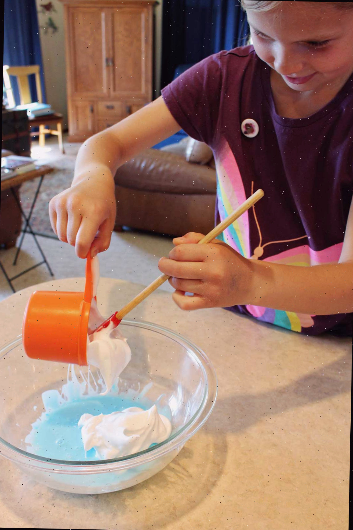 Menina jovem usando blusa marrom adiciona creme de barbear a um lote de slime fofo.