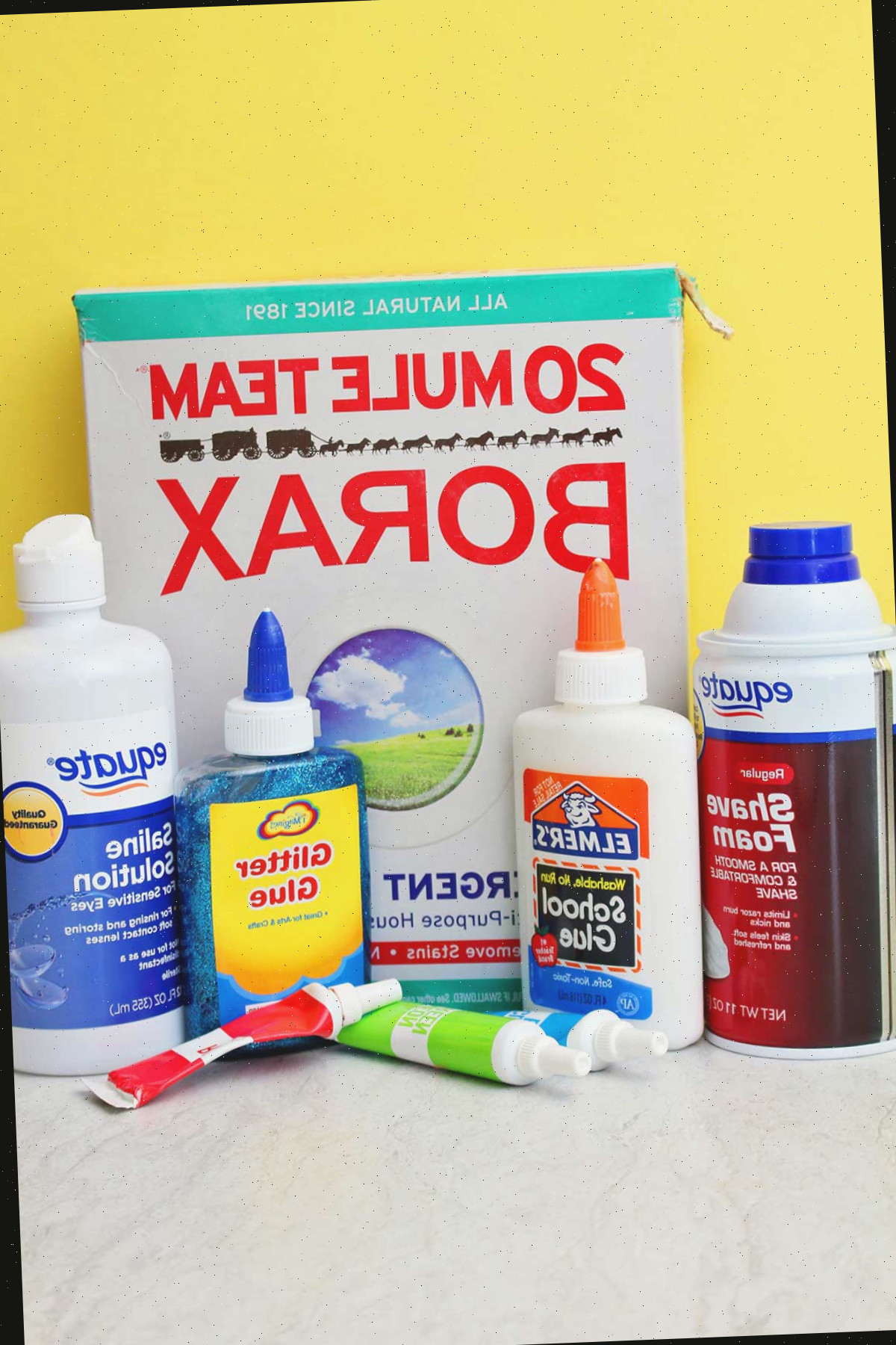 Todos os materiais necessários para fazer um lote de slime fofinho em um fundo amarelo.