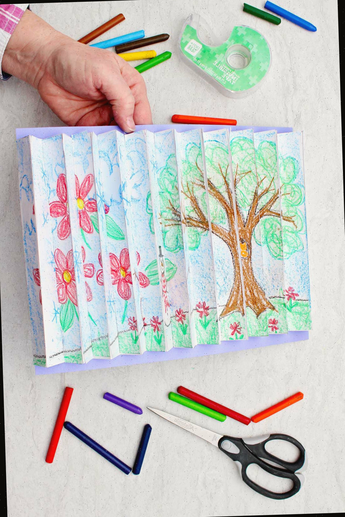 Indivíduo segurando a imagem do agamógrafo finalizado em um ângulo para visualizar a imagem de uma árvore na estação de primavera com suprimentos ao redor.