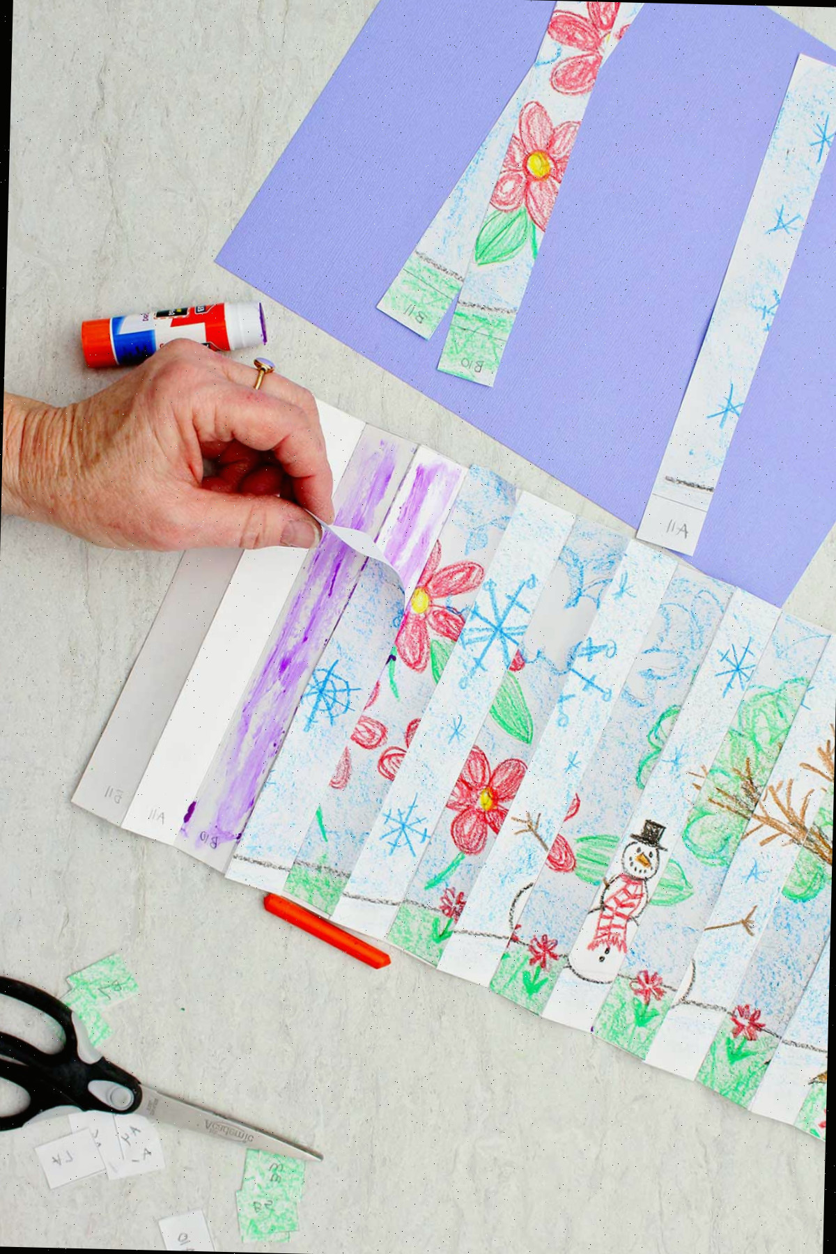Indivíduo utilizando um bastão de cola para colar tiras dos dois desenhos de diferentes estações em um papel branco longo, alternando a tira de inverno e a tira de primavera.