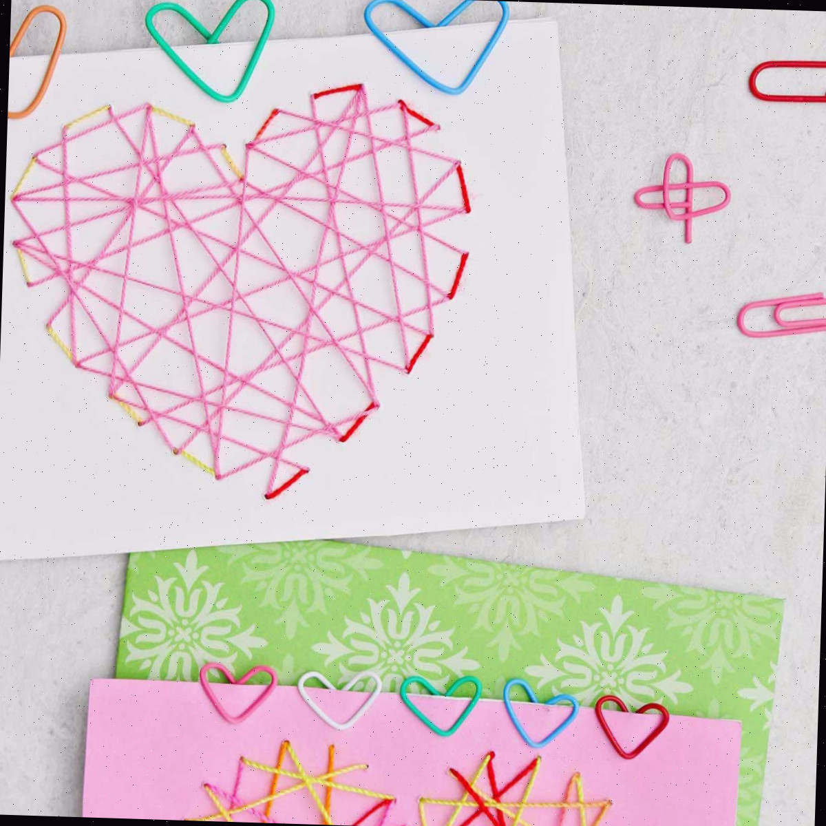 Dois cartões de Dia dos Namorados com clipes de papel coloridos em forma de coração presos a eles.
