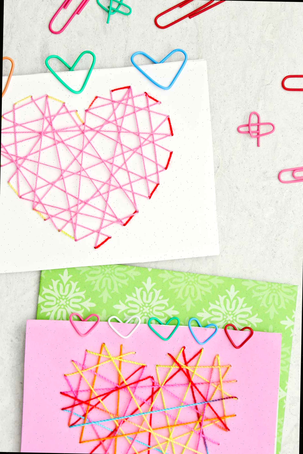 Dois cartões de Dia dos Namorados com clipes de papel coloridos em forma de coração presos a eles.