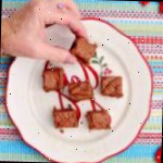 Uma pessoa pegando um pedaço de fudge de um prato de festa.