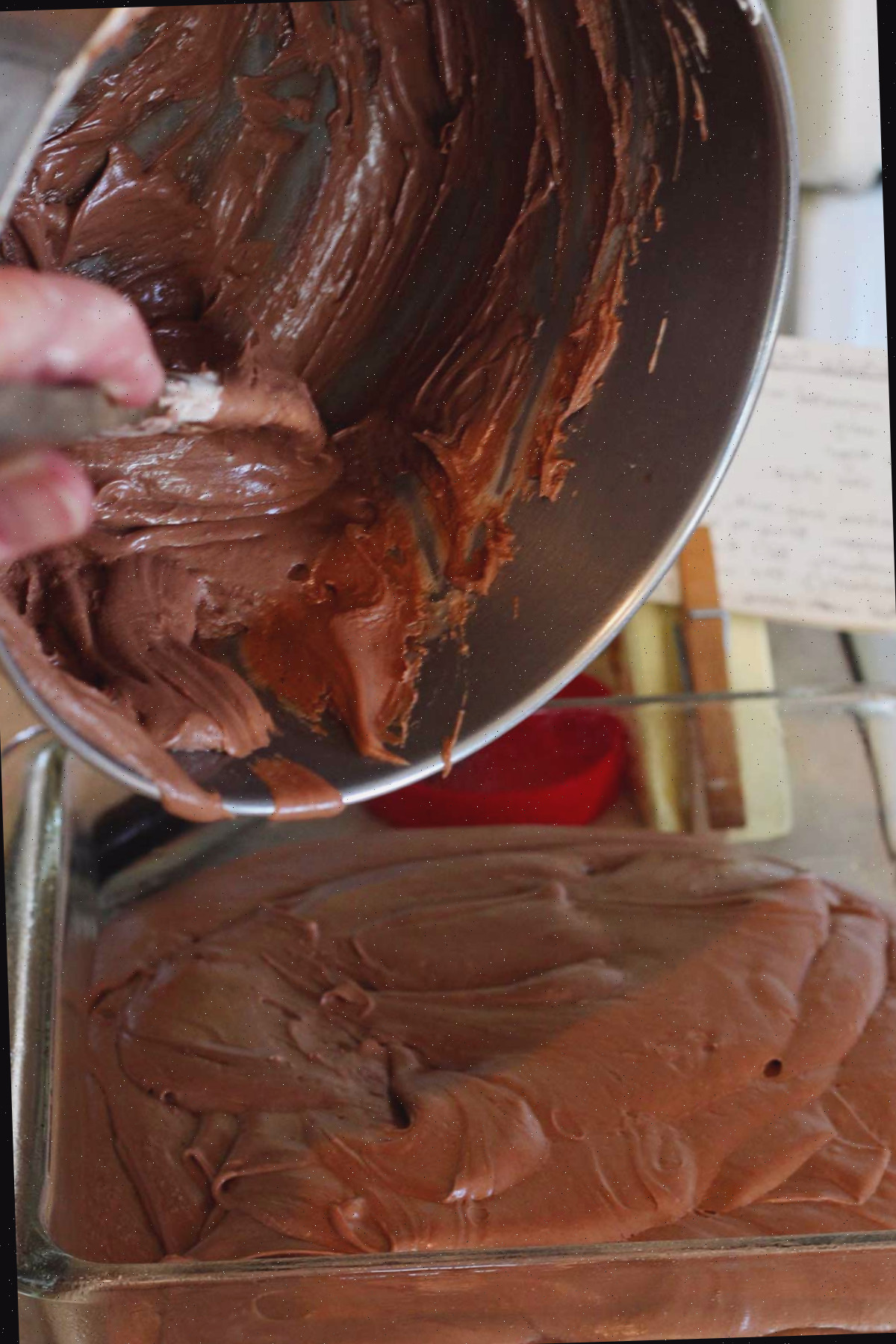 Pessoa retirando a mistura de fudge da panela para a forma de vidro.