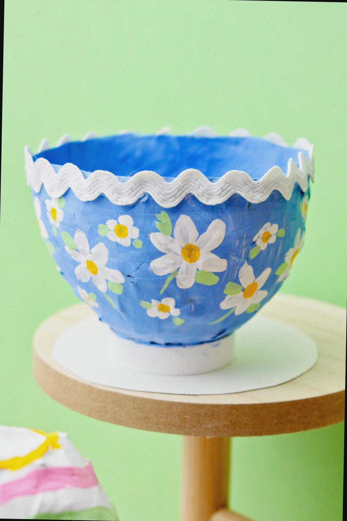 Uma encantadora tigela de papel machê azul decorada com flores pintadas e uma borda de rick rack.