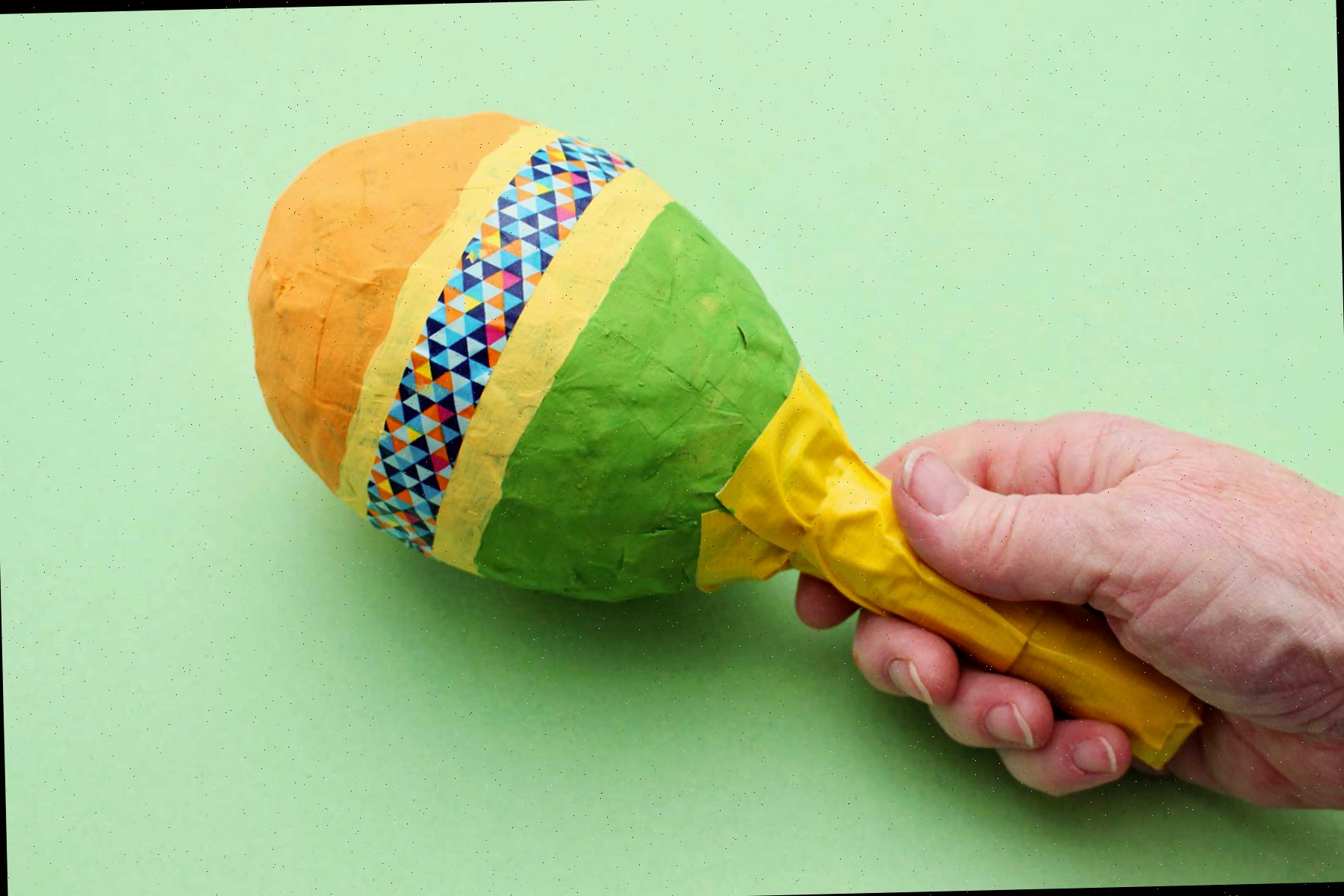 Uma pessoa segurando uma maraca de papel machê.