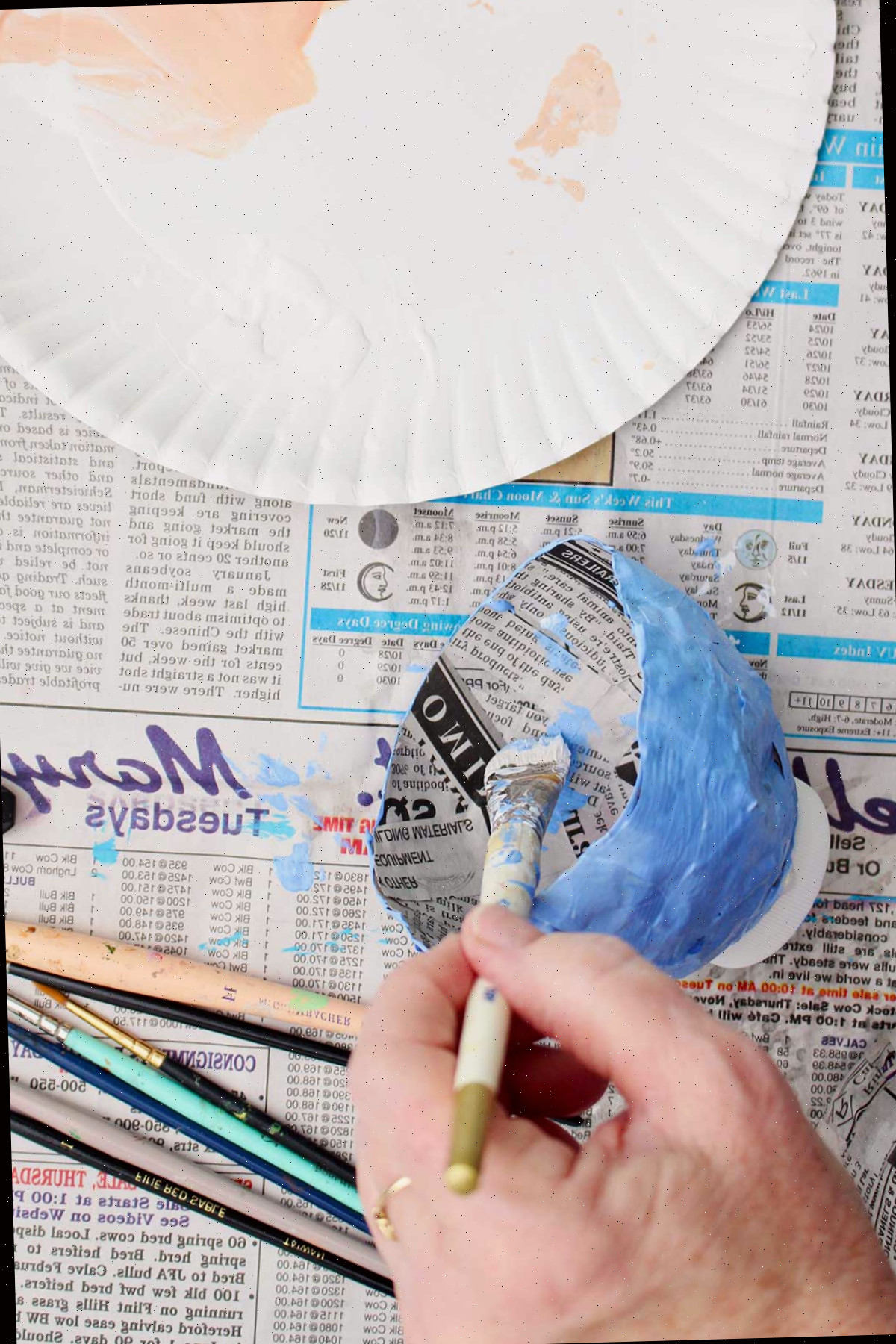 Uma pessoa pintando o interior do seu projeto de papel machê seco de azul claro.