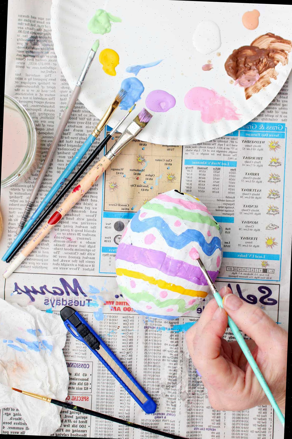 Uma pessoa pintando um ovo de páscoa de papel machê.