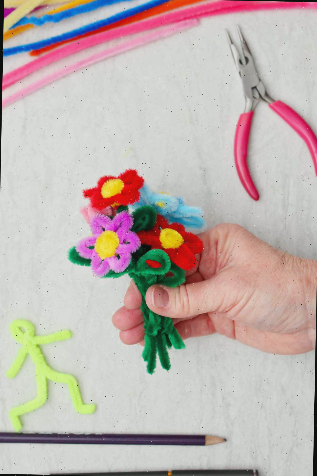 Uma pessoa segurando um buquê de flores de limpadores de tubo de várias cores.