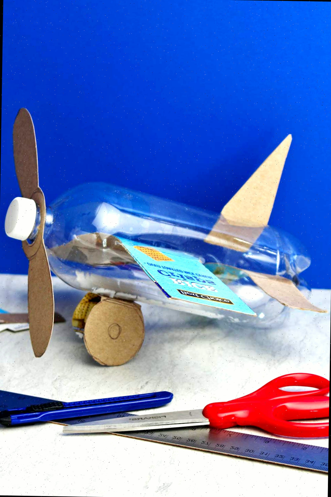 Avião de garrafa completo antes da pintura spray contra um fundo azul.
