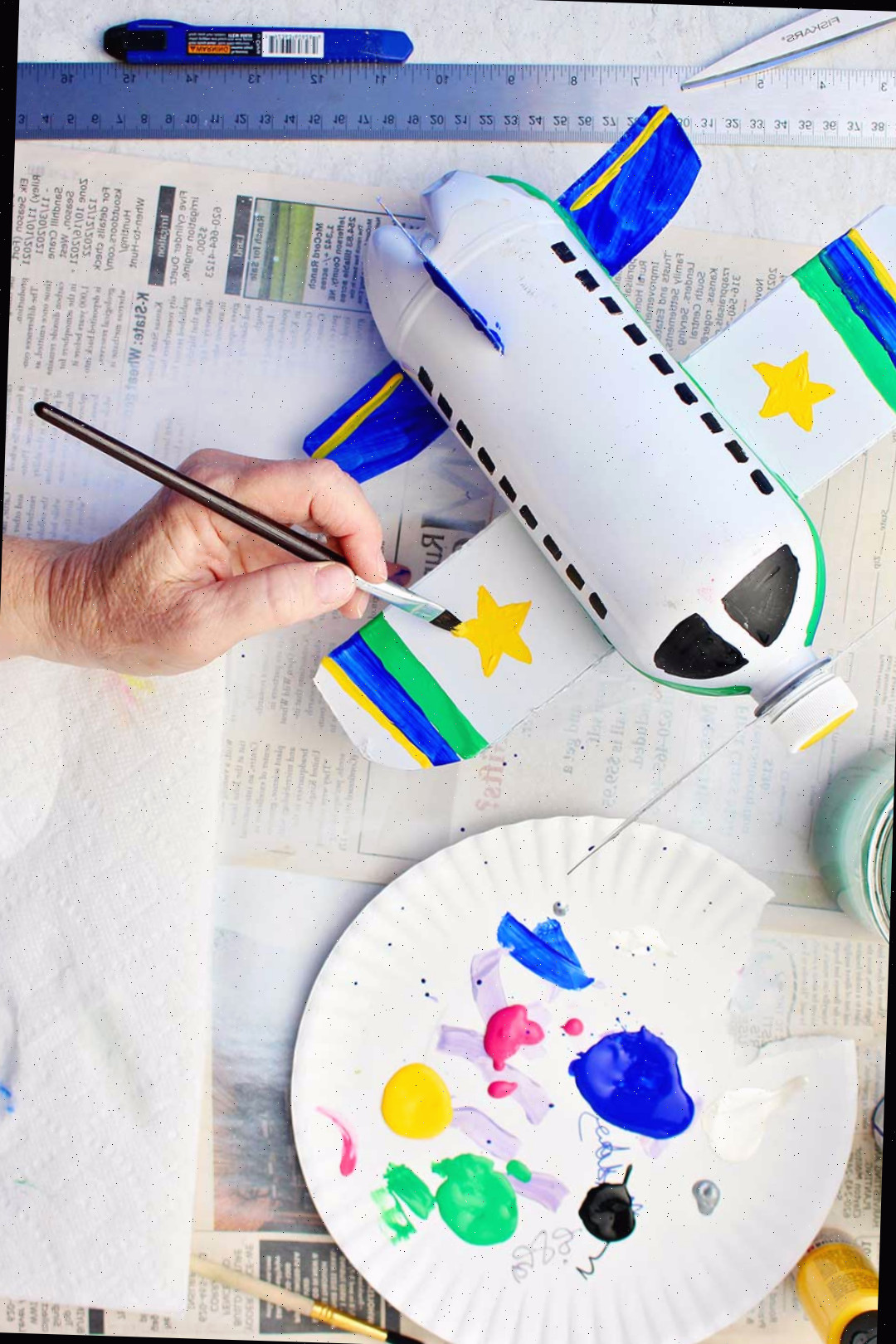 Pintando detalhes nas asas, como listras e estrelas, no avião de garrafa branco.