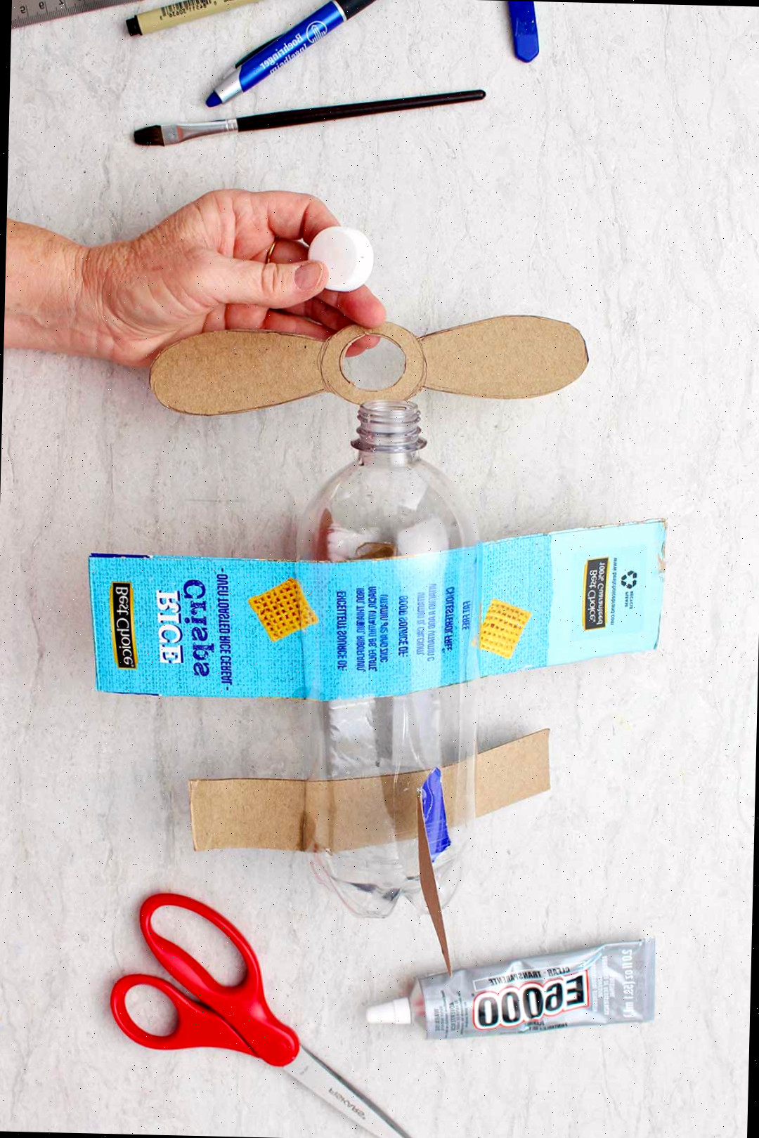 Mão fixando hélices de papelão no bocal da garrafa.