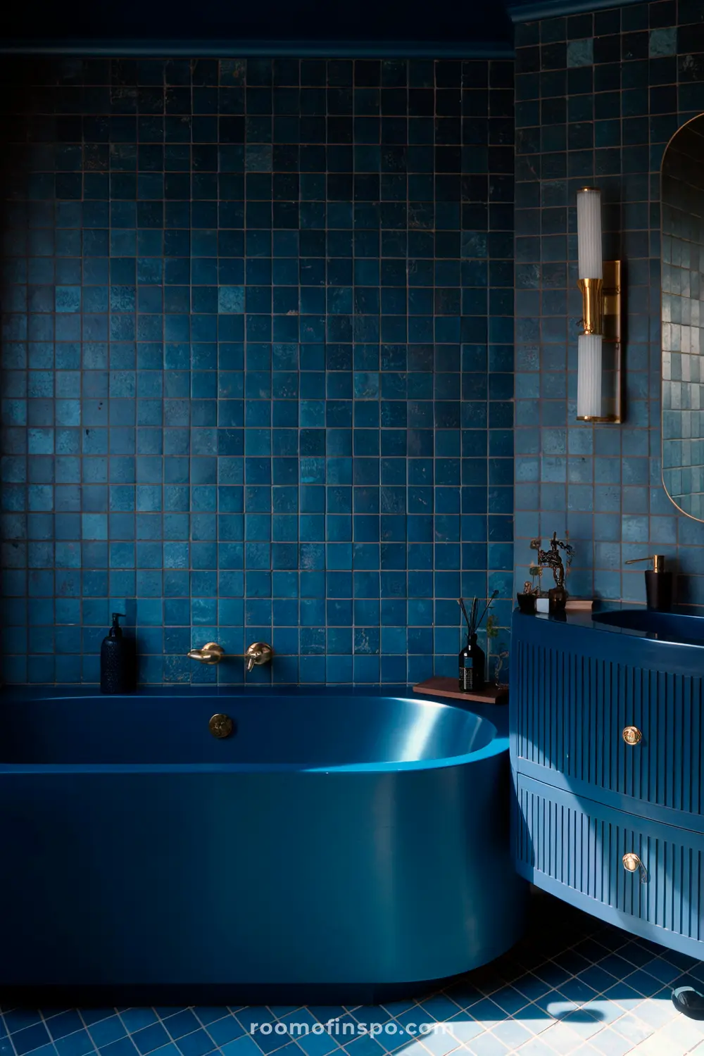 Um banheiro azul sombrio com paredes azul-marinho, uma banheira azul elegante, azulejos texturizados e acessórios dourados que adicionam calor.