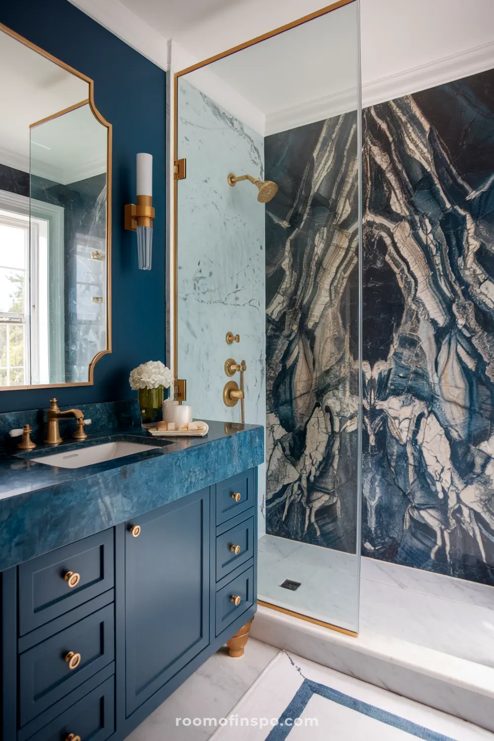 Um banheiro azul escuro com uma vaidade de mármore azul, acessórios dourados e uma parede de chuveiro de mármore.