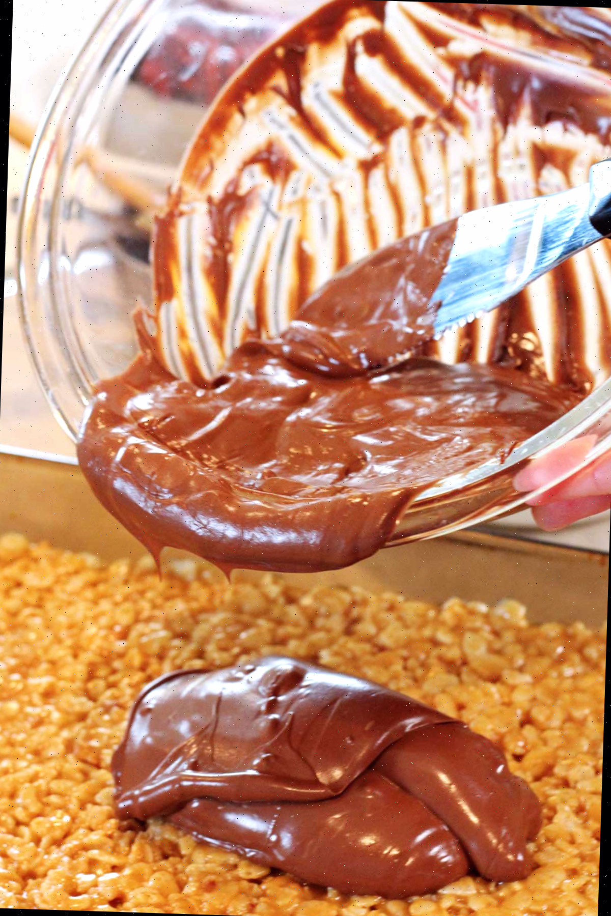 Uma pessoa despejando chocolate derretido de uma tigela sobre os scotcharoos.