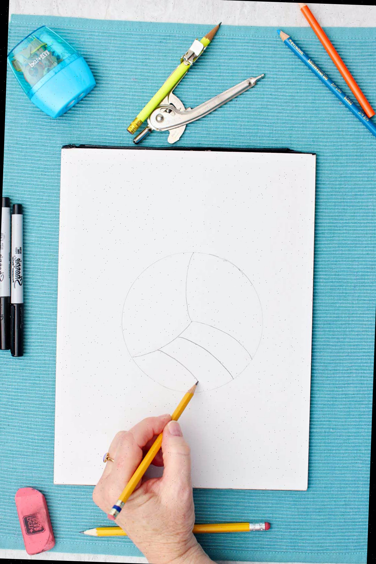 Pessoa esboçando linhas de detalhe no desenho de vôlei com lápis.