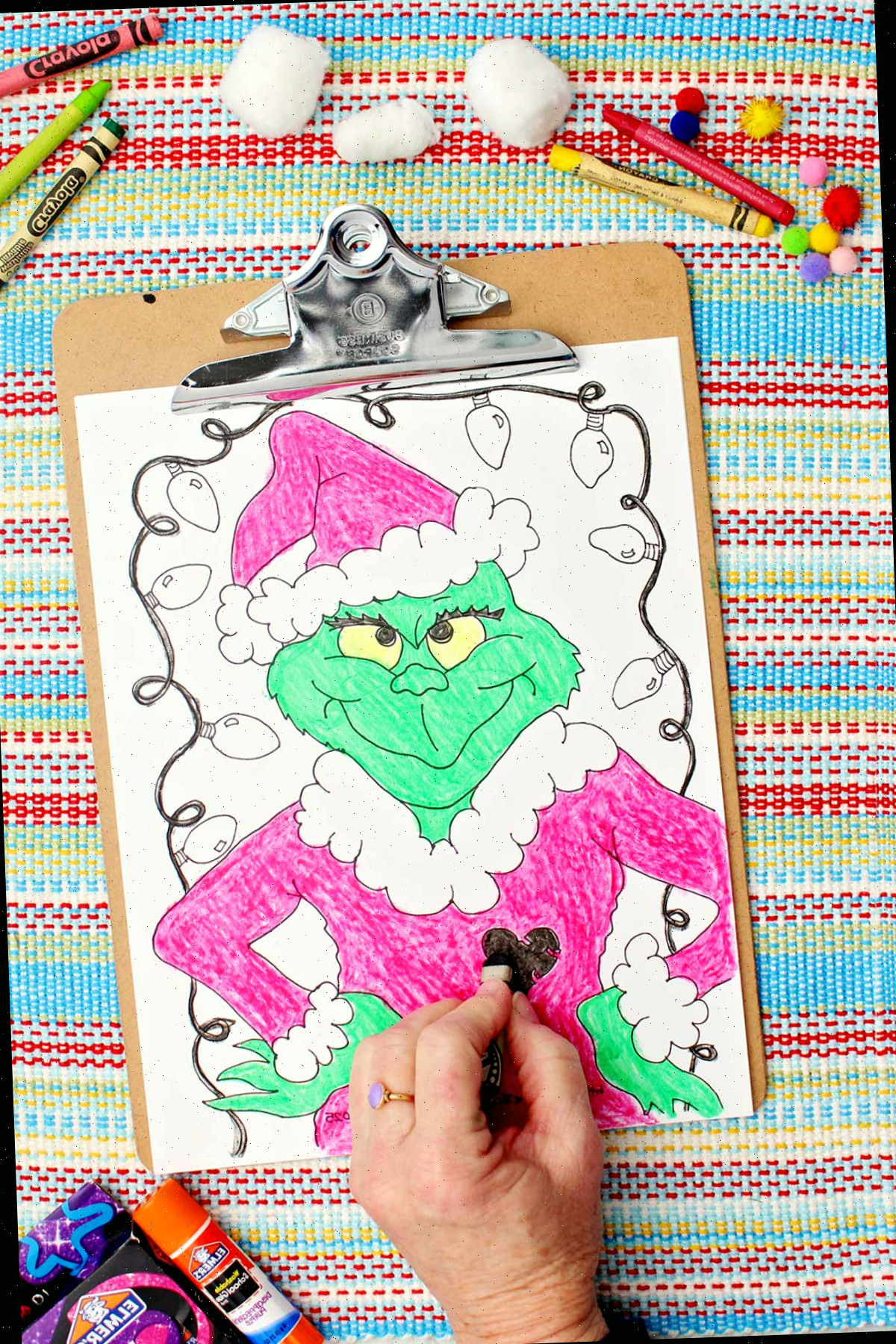 Indivíduo colorindo um coração no casaco na folha de colorir do Grinch.