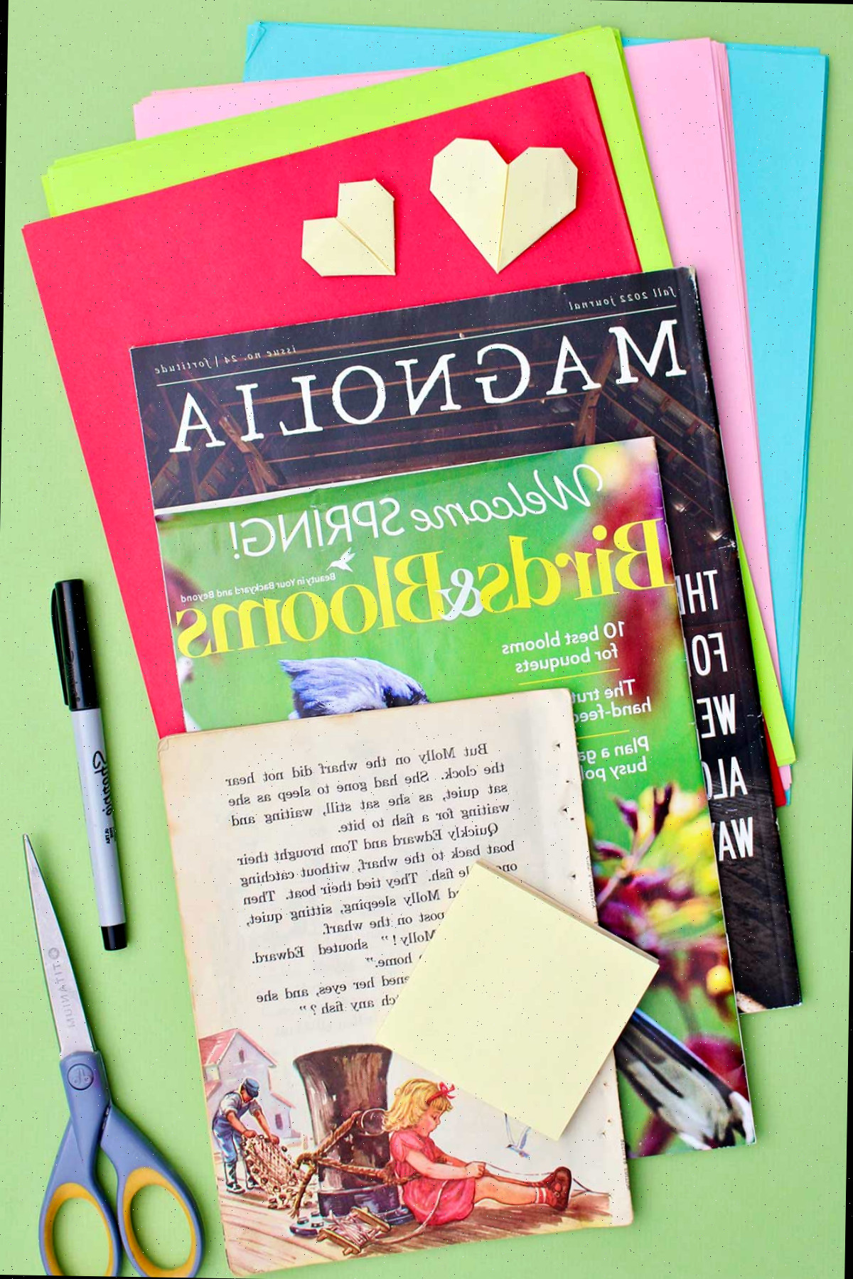 Páginas de revistas e papéis coloridos, tesouras, um marcador e notas adesivas.
