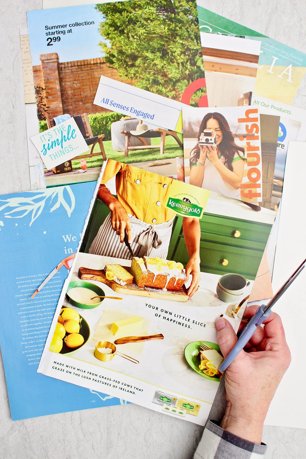 Uma pessoa segurando uma tesoura e alguns recortes de revistas coloridas para um quadro de visualização.