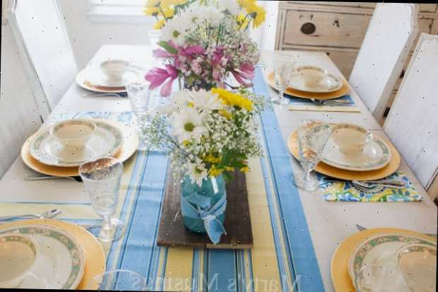 Uma mesa com um vaso de flores sobre um prato, com azul e primavera