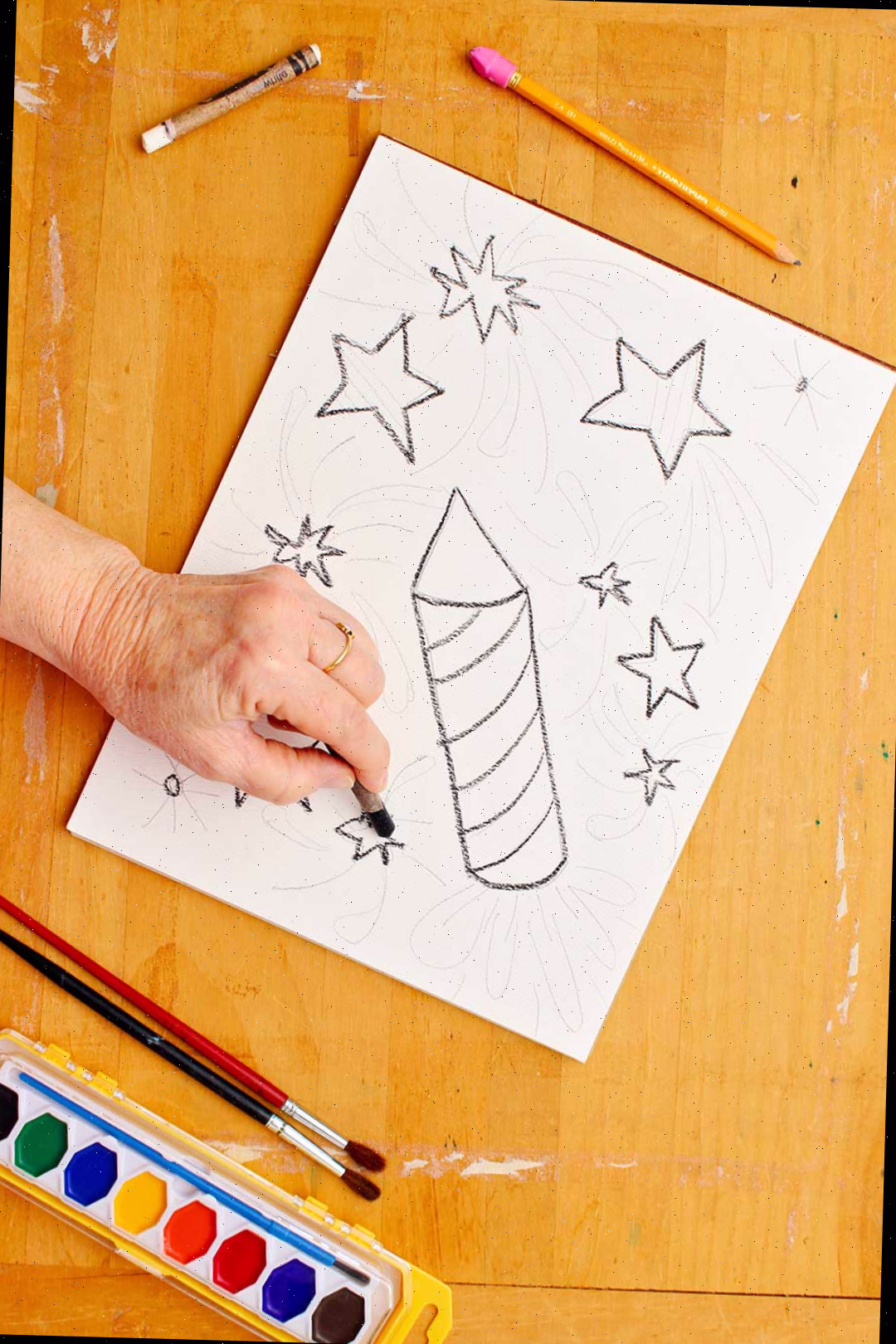 Desenhando estrelas com giz de cera preto no papel.