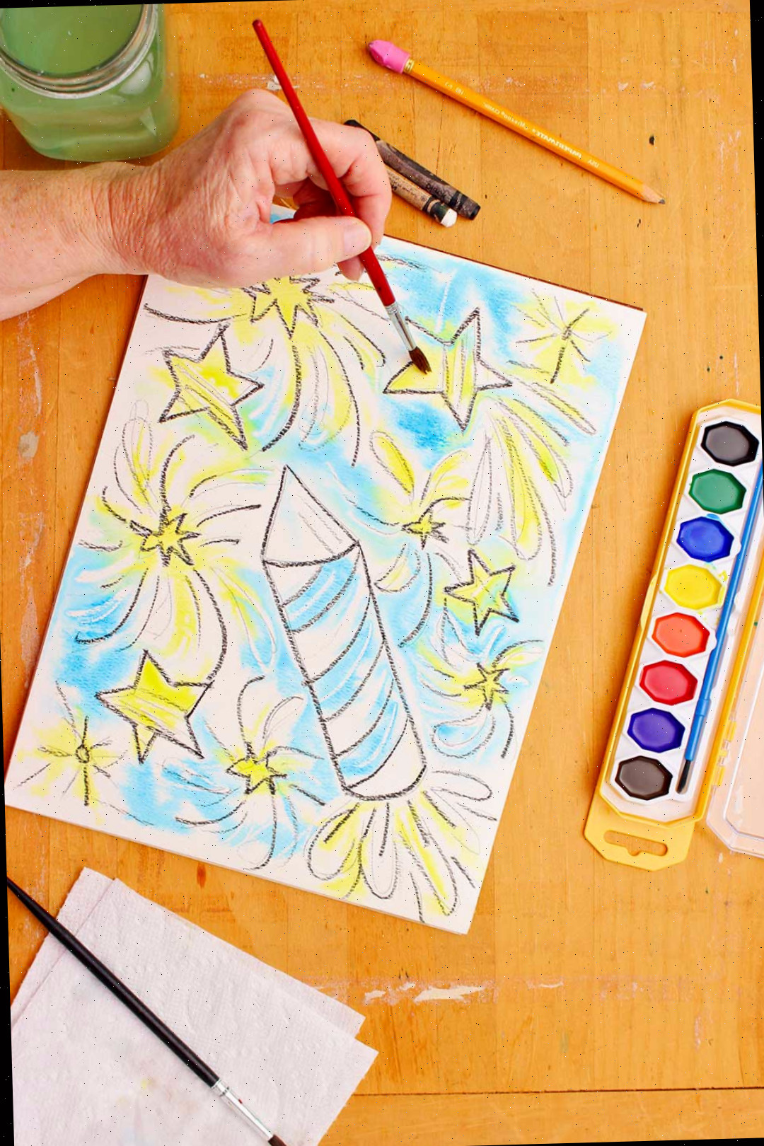 Mão pintando estrelas amarelas na resistência em aquarela.