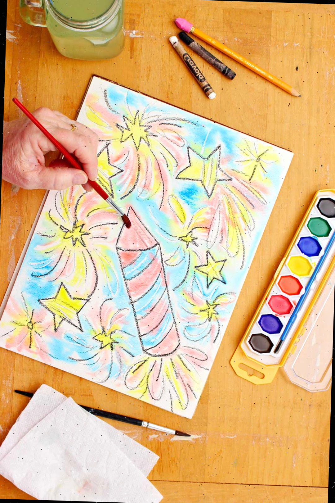 Mão pintando a ponta do foguete na resistência com aquarela.