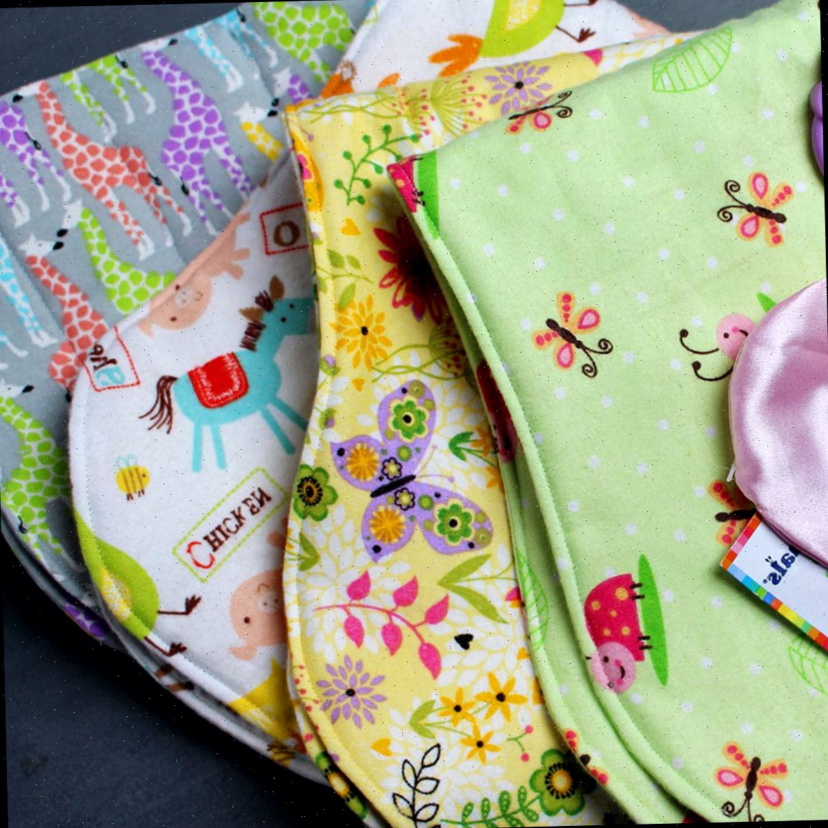 Uma pilha de fraldas de bebê feitas de impressões de tecido de feltro colorido.