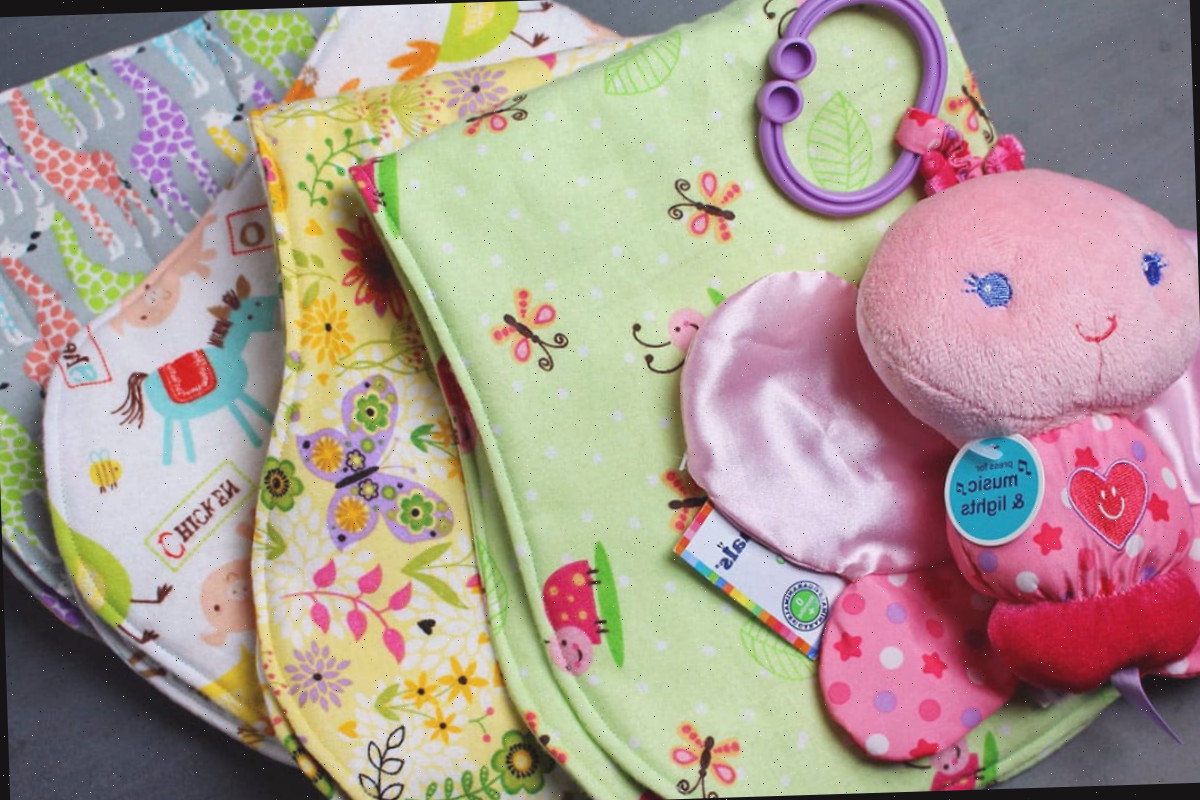 Uma pilha de toalhas de arroto para bebês feitas de estampas de tecido de feltro colorido.