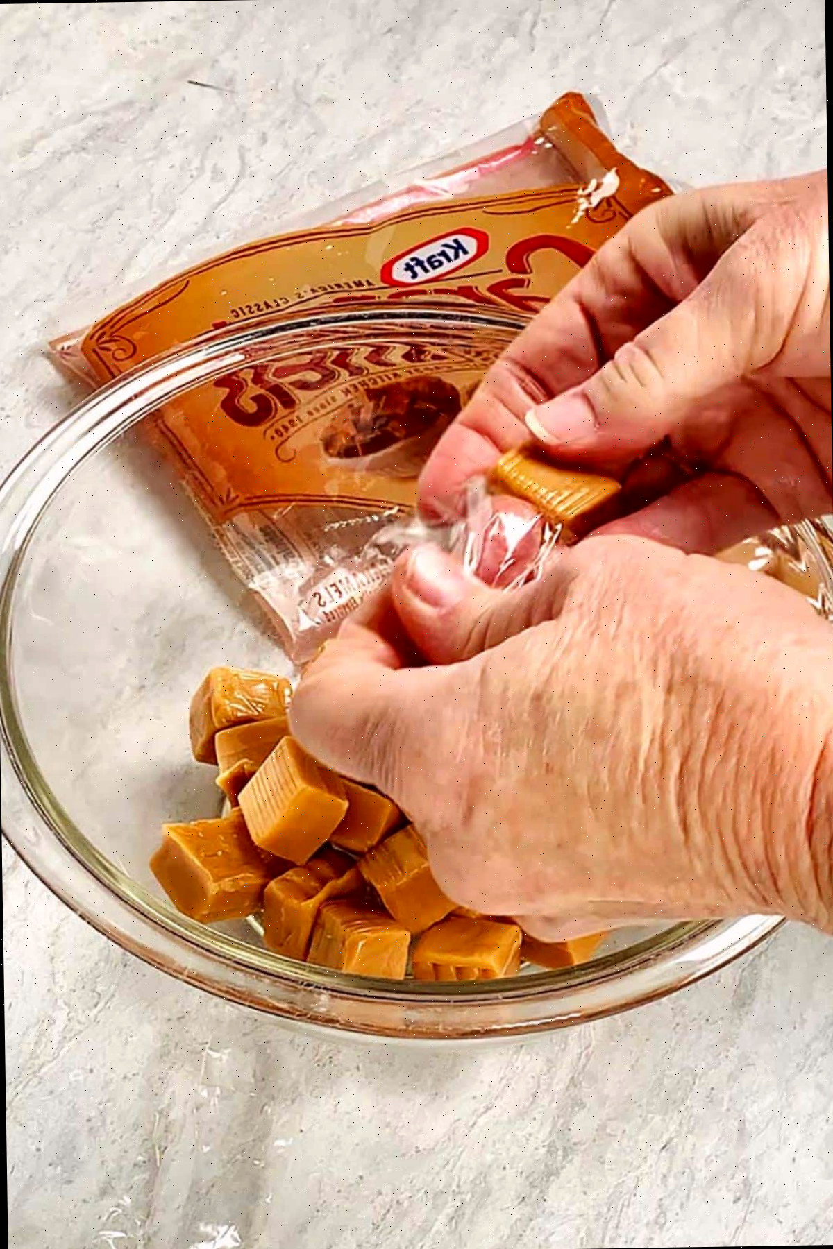 Pessoa desembrulhando Caramelos Kraft em uma tigela de vidro.
