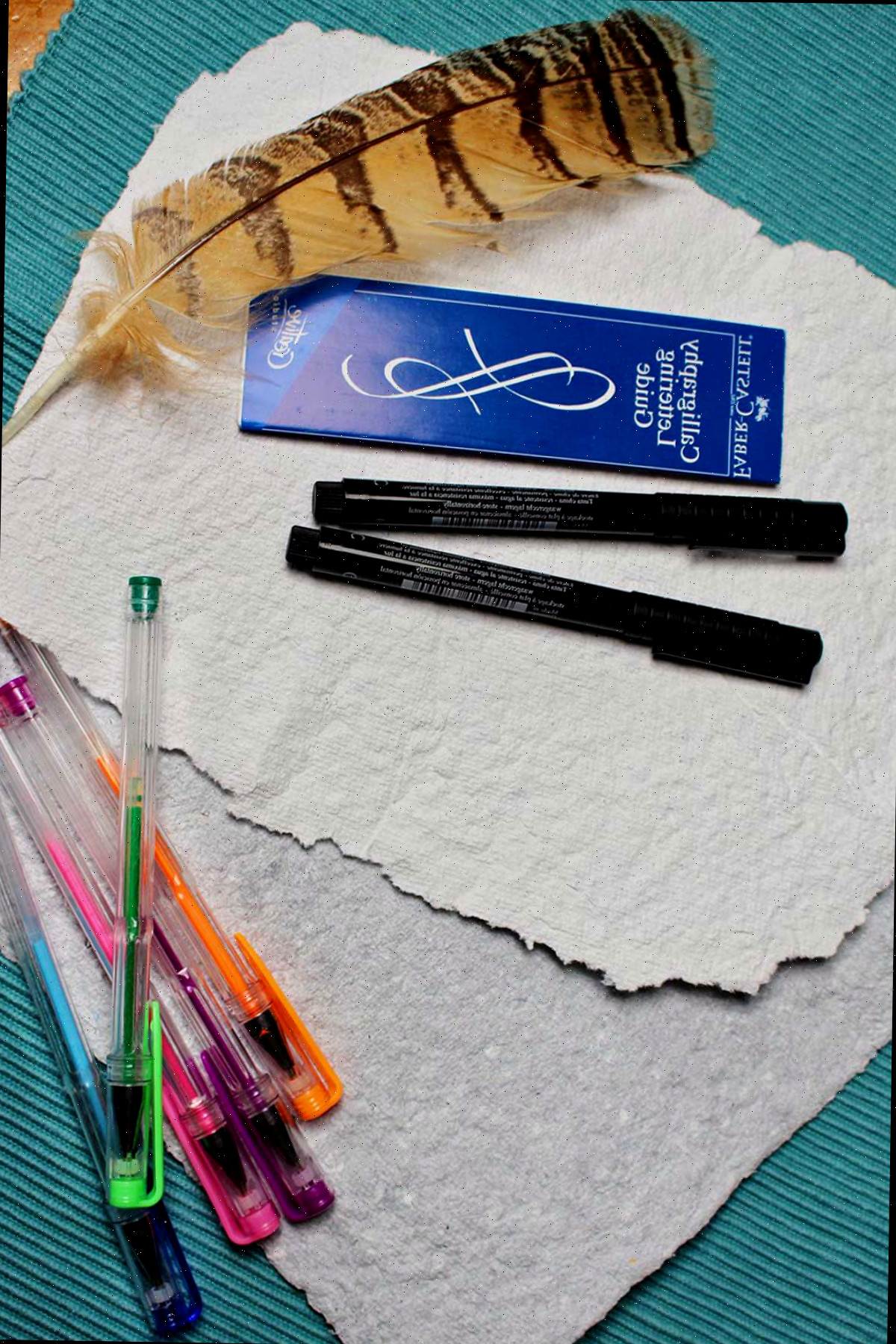 Folhas de papel reciclado, canetas em gel, marcadores, uma pena.