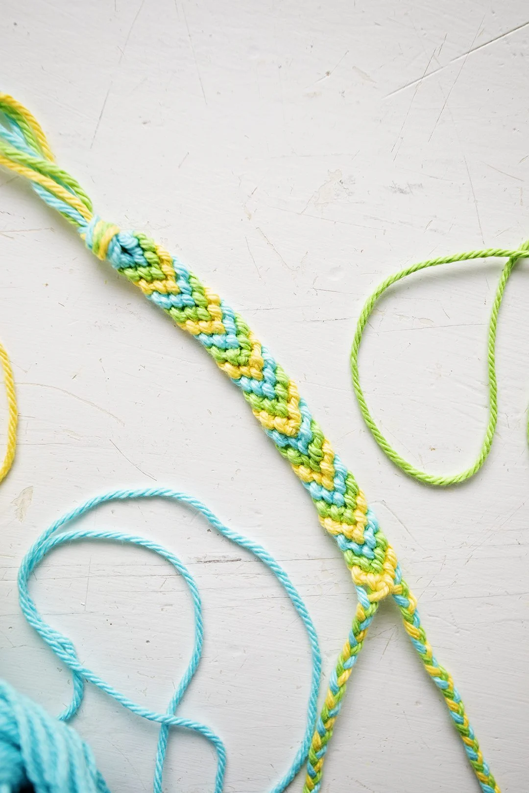 Um padrão de pulseira em Chevron feito de fios azuis, verdes e amarelos.