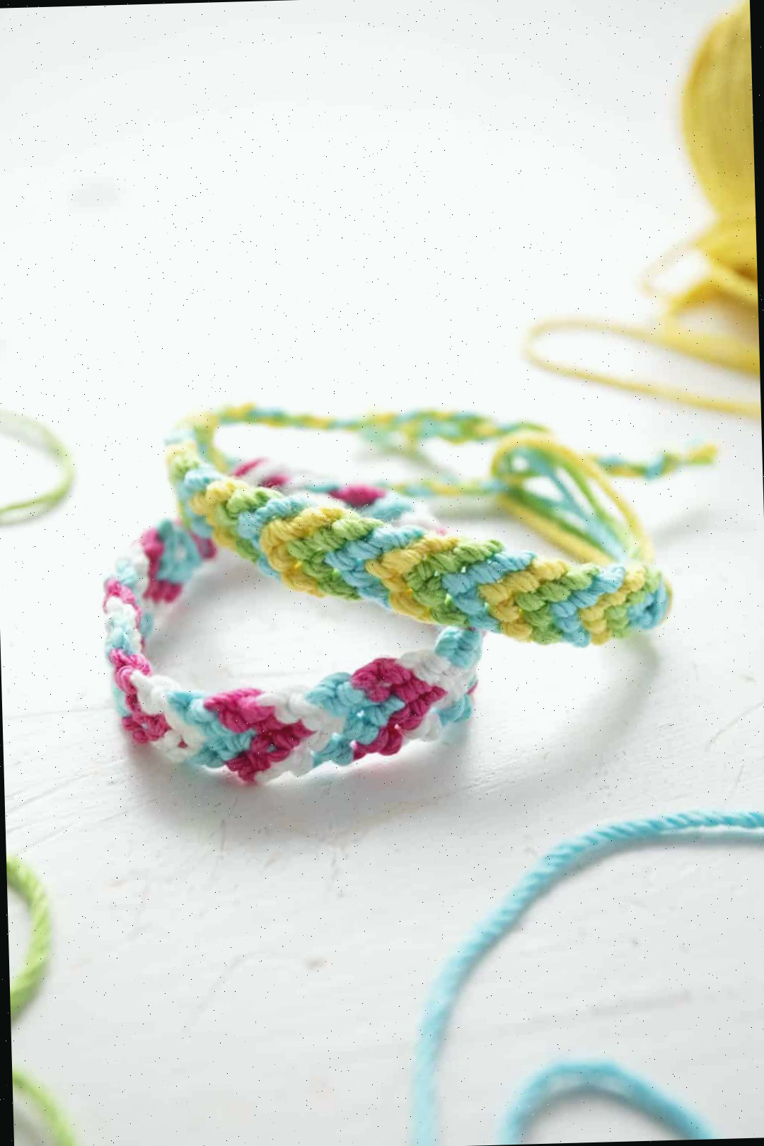 Duas pulseiras em padrão Chevron em linha de bordado verde, azul, amarelo, rosa e branca.