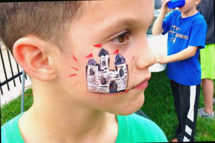 Menino jovem do lado de fora com camiseta verde e pintura facial de castelo.
