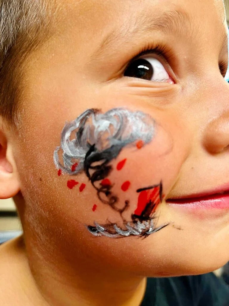 Menino jovem com olhos marrons em close da pintura facial de tornado.