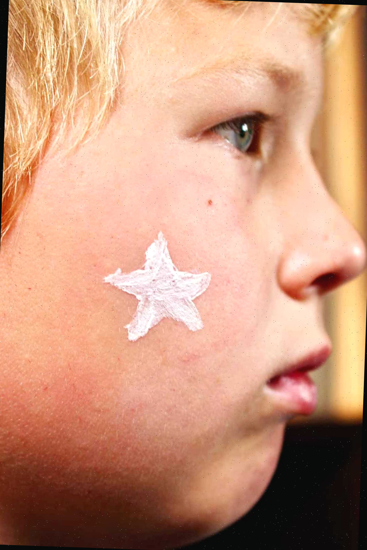 Perfil de menino com estrela branca pintada na bochecha.