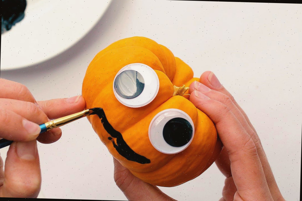 Pintando um sorriso em uma mini abóbora com olhos móveis.