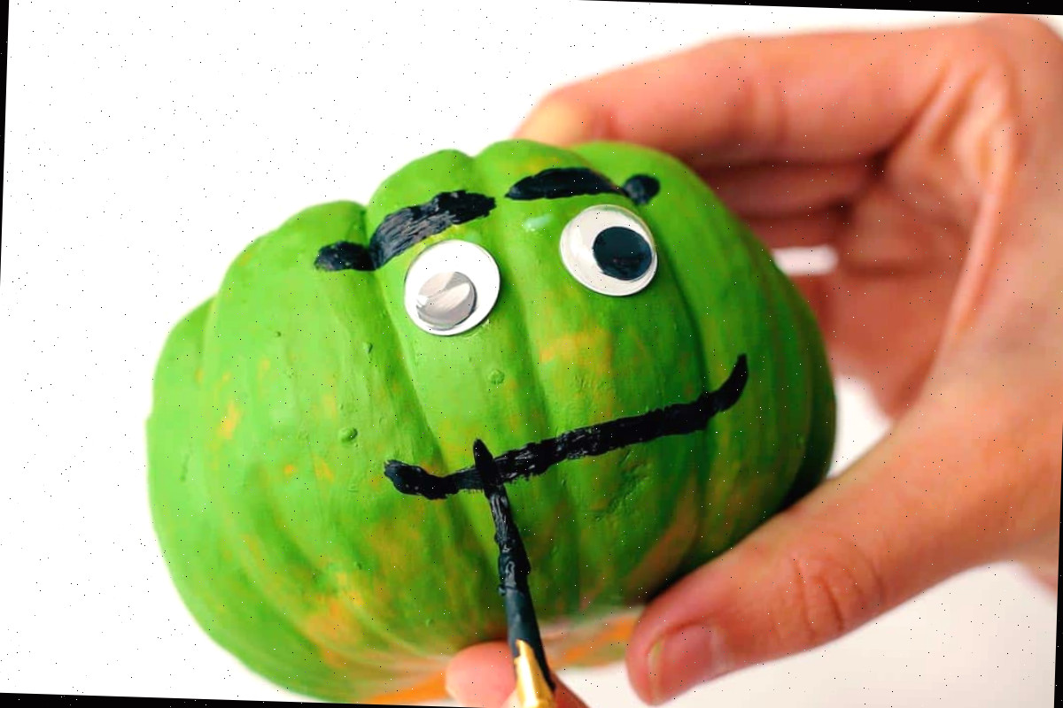 Pincel adicionando sorriso a um rosto de frankenstein em um artesanato de abóbora.