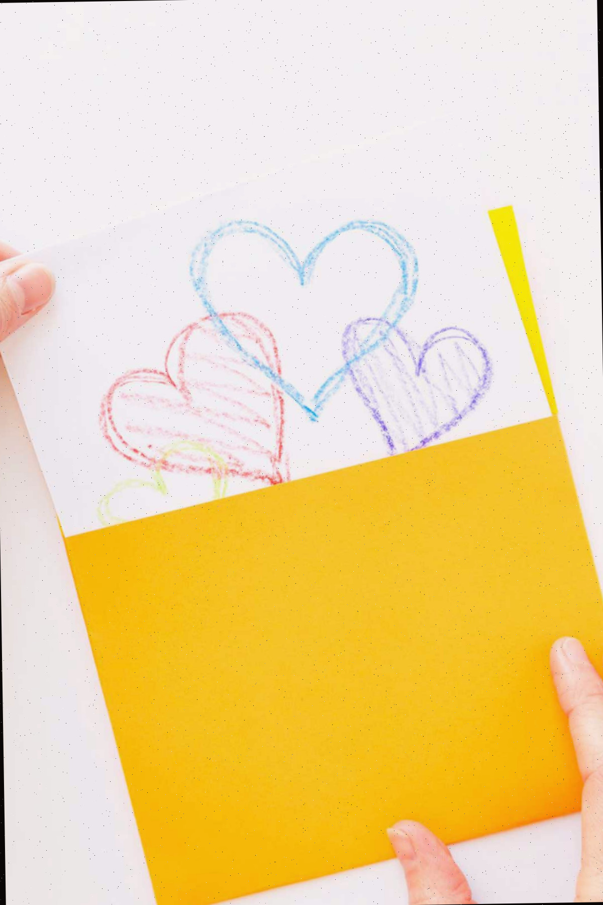 Puxando um cartão com corações multicoloridos de um envelope quadrado amarelo feito à mão.