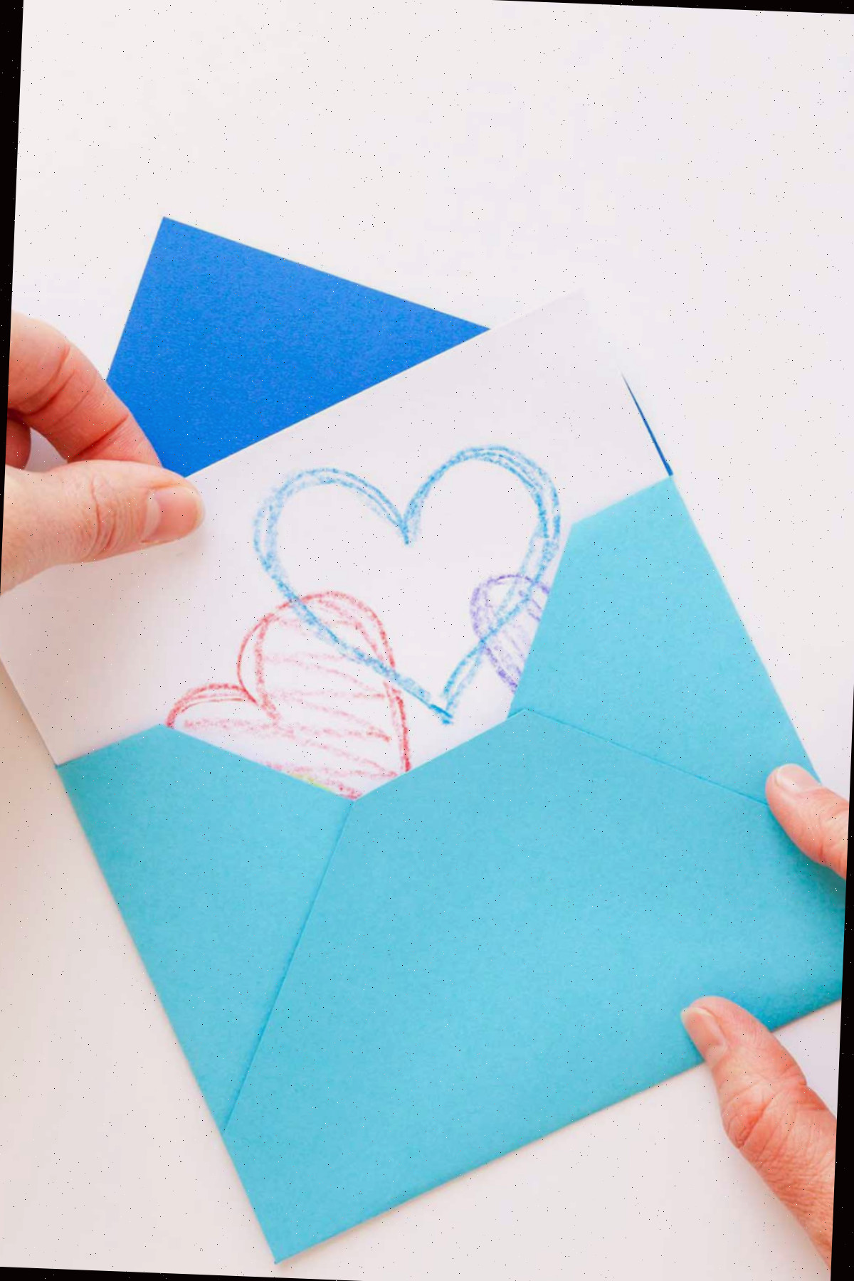Puxando um cartão com corações de um envelope tradicional azul feito à mão.