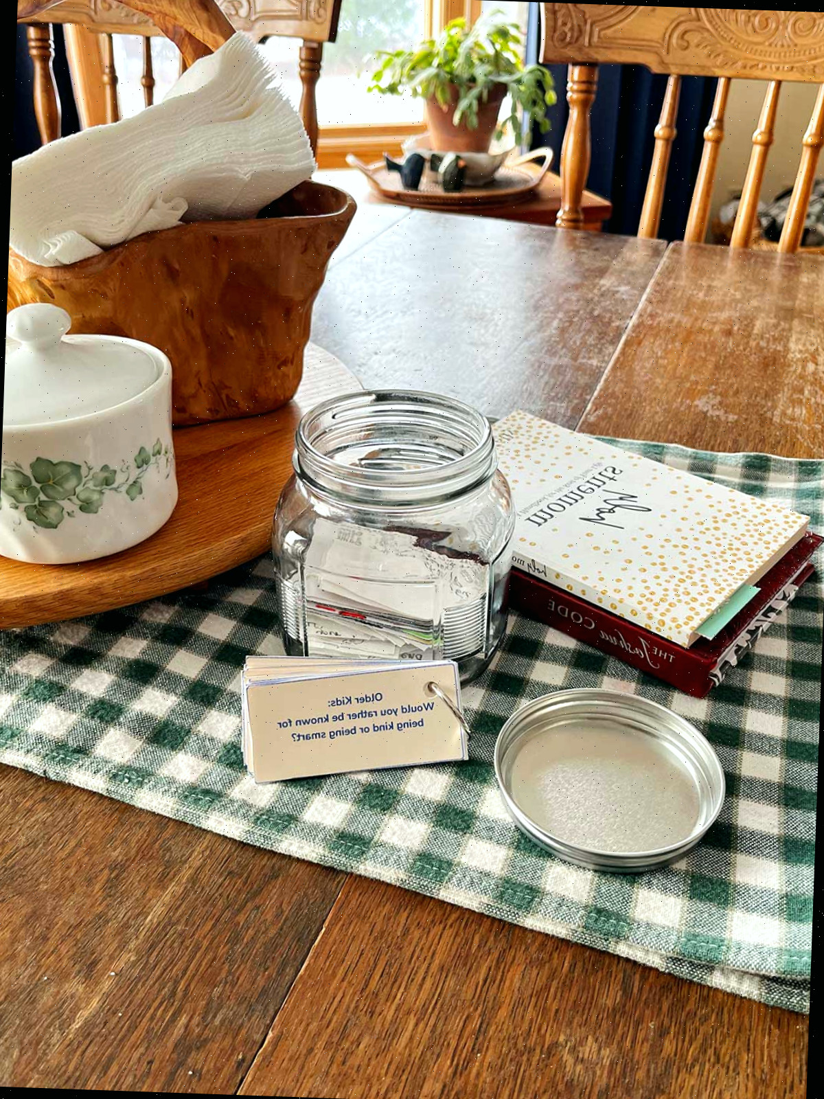 Uma pilha de perguntas 'Você Preferiria' ao lado de um pote em uma mesa.