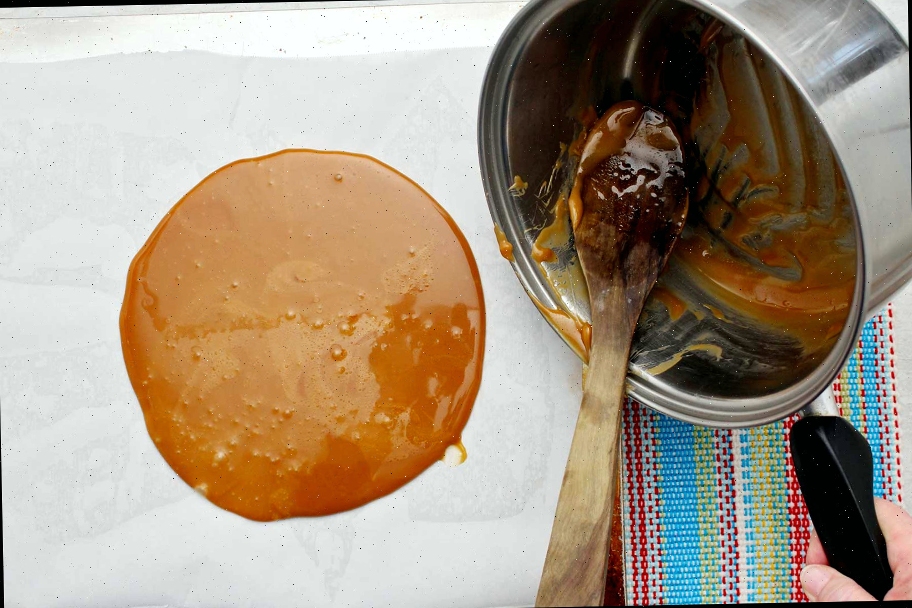 Uma pessoa despejando a mistura de tâfee no papel manteiga.