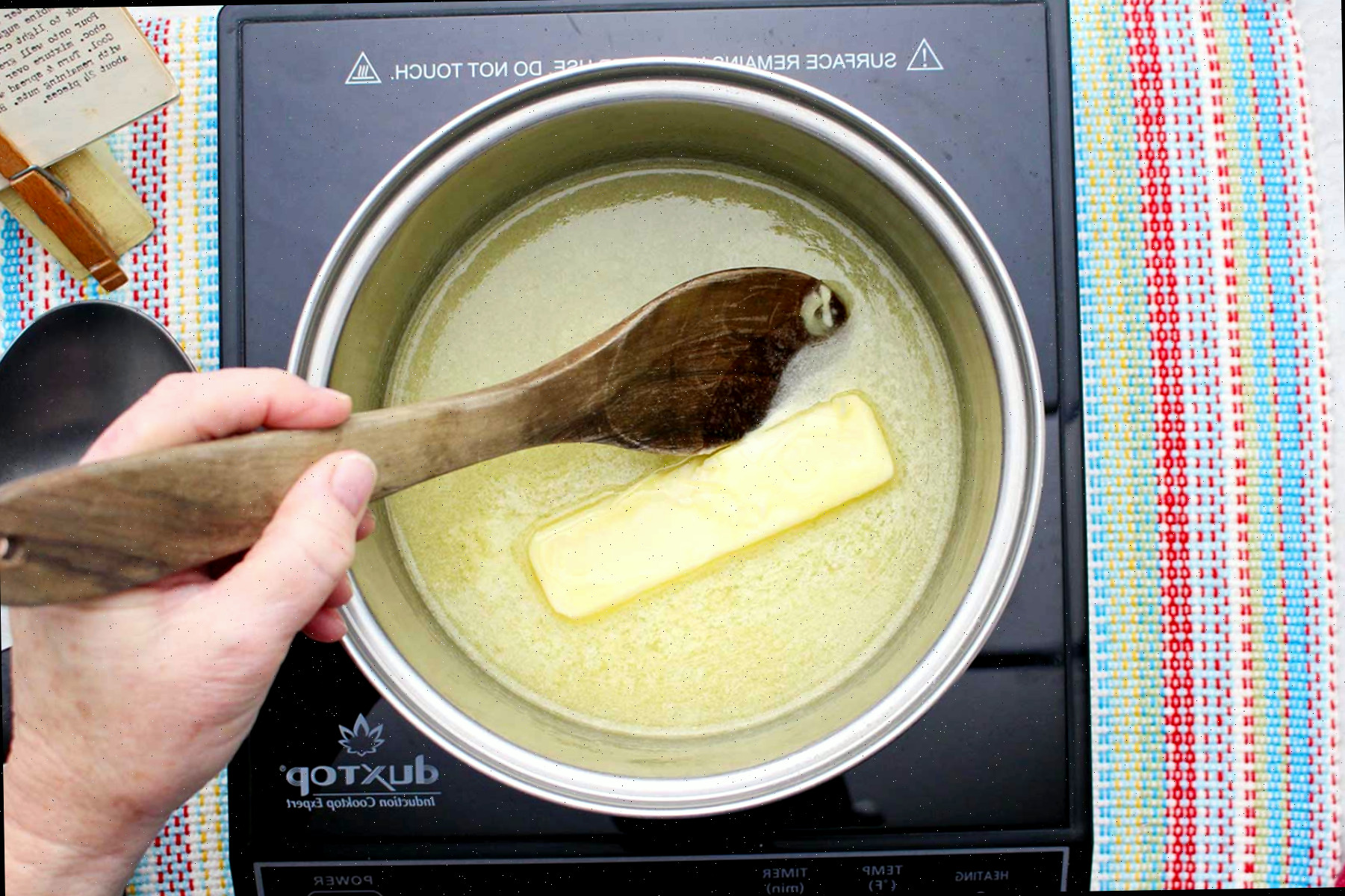 Uma pessoa derretendo manteiga em uma panela.