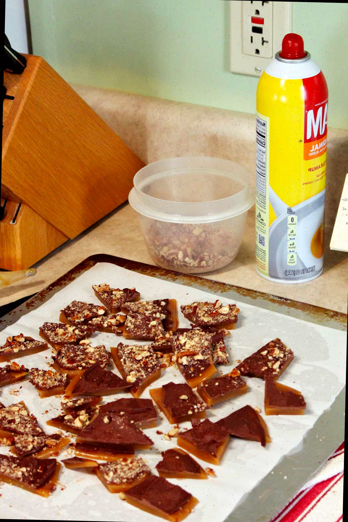 Pedaços quebrados de tâfee no papel manteiga sobre o balcão.