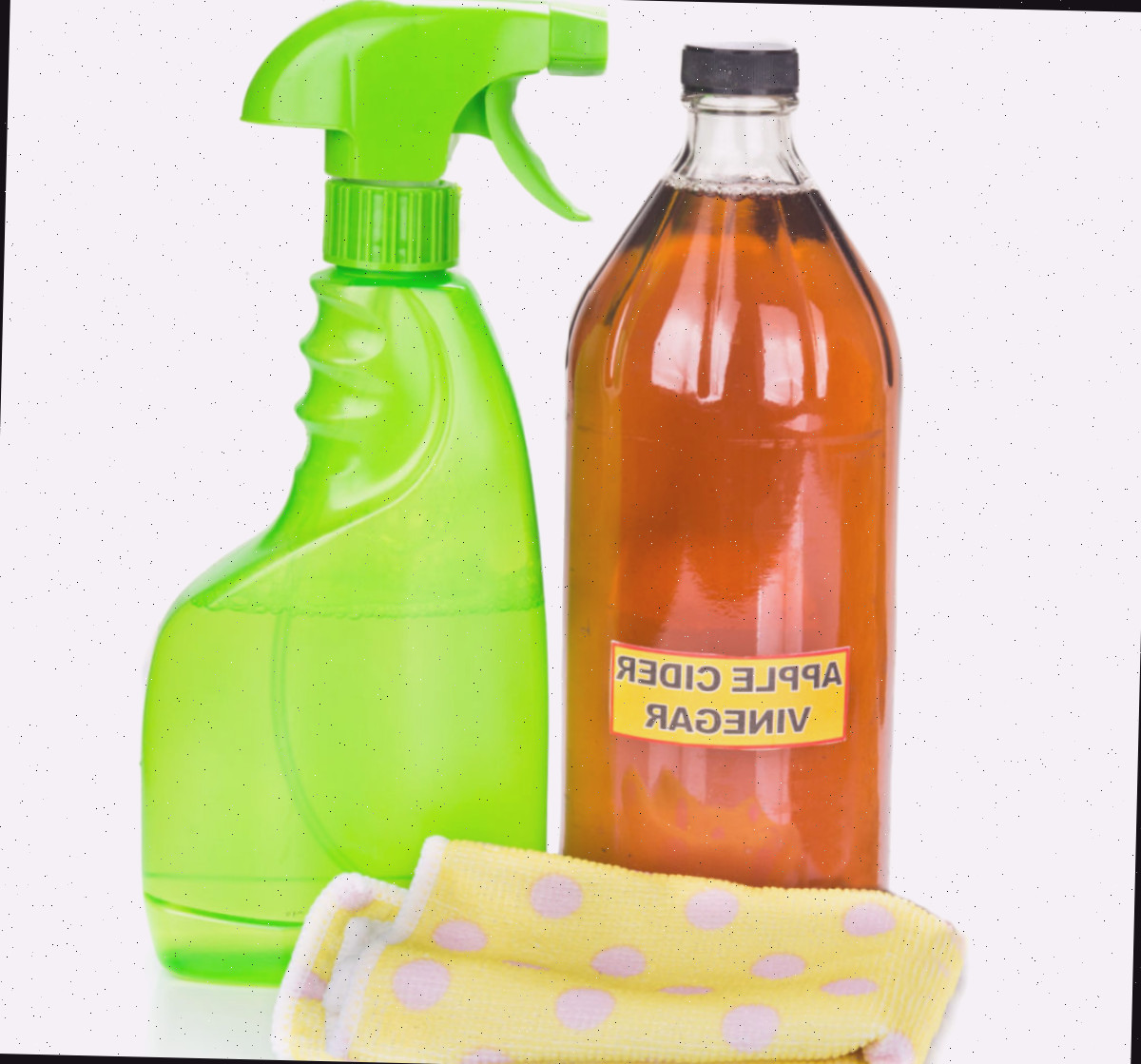 Vinagre de maçã em uma garrafa ao lado de um pano de limpeza e uma garrafa de spray verde.