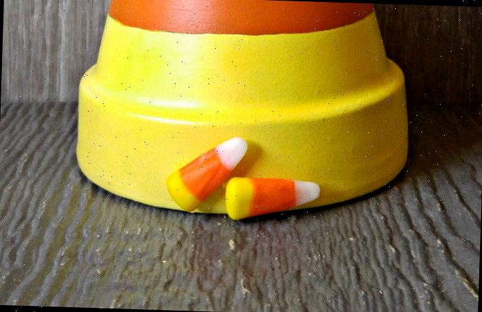 Doces de milho colados na parte inferior de um vaso de barro pintado de ponta-cabeça.