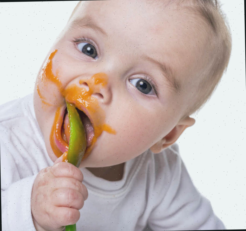 Infant with food on face. Bebê com colher e comida no rosto.